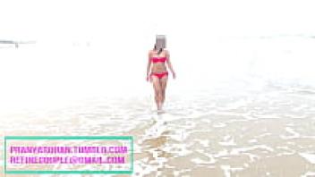 Pranya strolling along the shore in a sexy red bikini