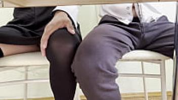 Under a table, a student girlfriend masturbates.