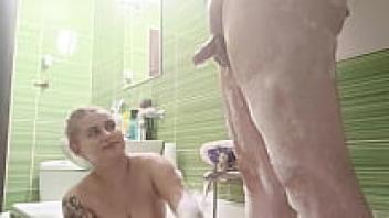 In the bathtub, a gorgeous blonde with large, natural tits cleans his dick.